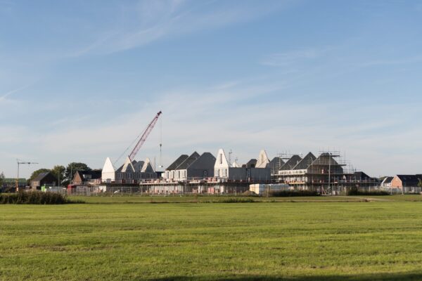 Houses,Being,Built,,Construction,Of,New,Homes,Behind,A,Field